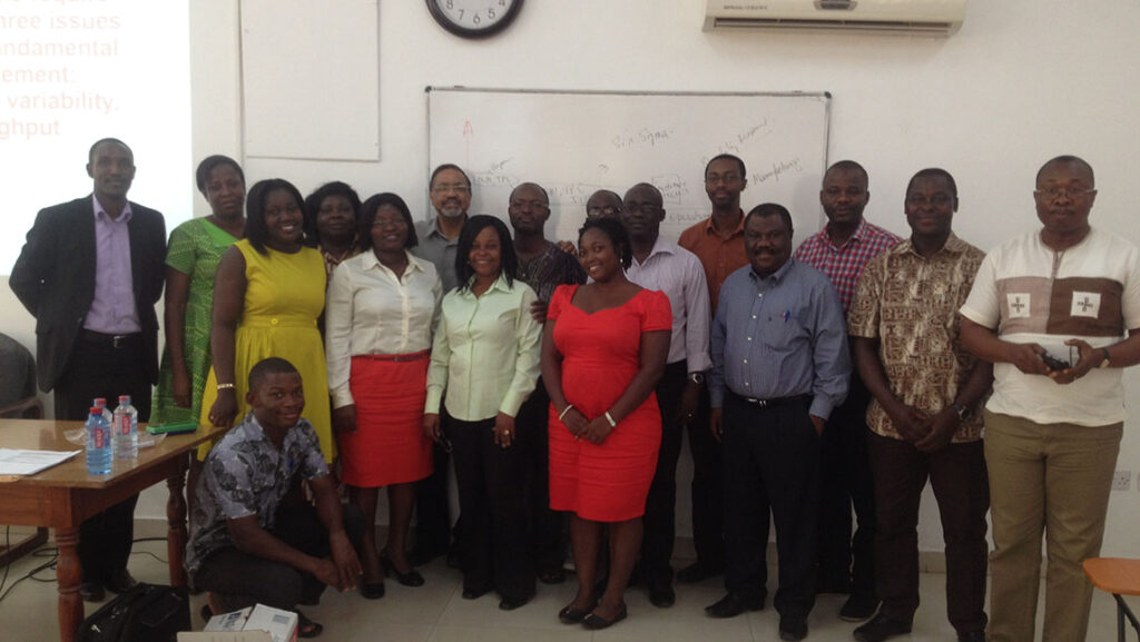 UNCG Dr. Joy Bhadury stands with a group of people in a South Africa classroom.