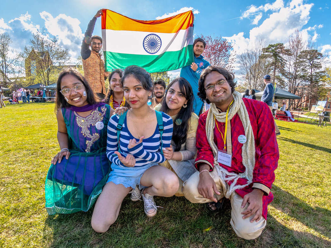 students kneel on the grass together at the international festival